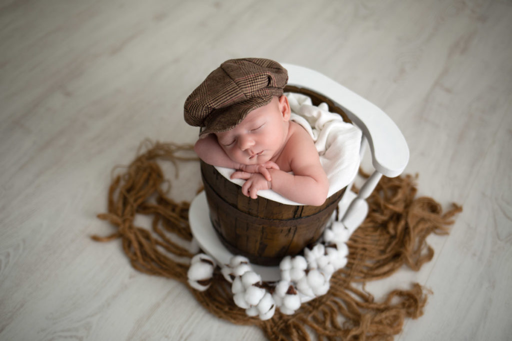 Bébé avec casquette dans un seau effet bois