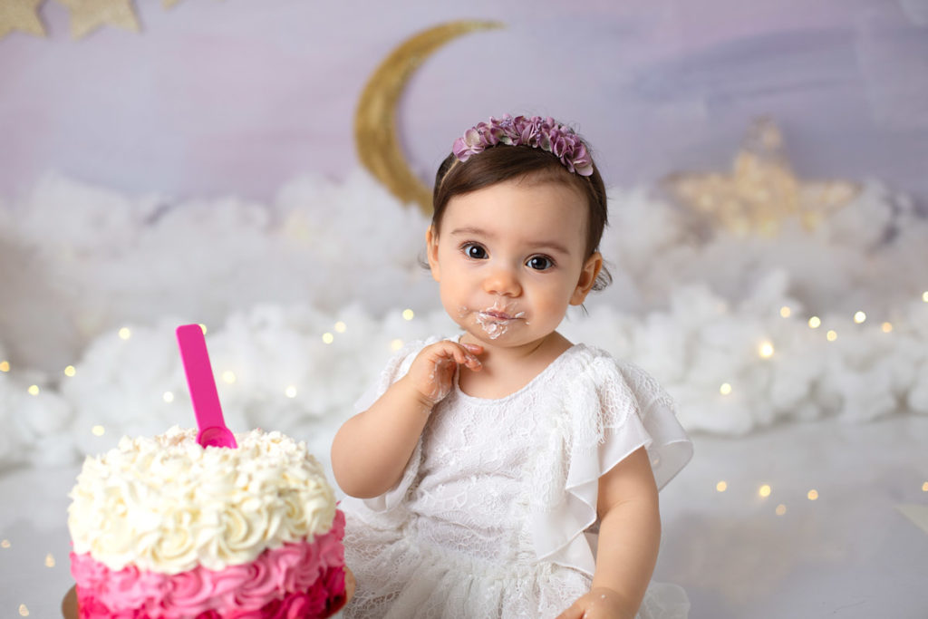 Petite fille mangeant du gâteau rose pour ses 1 an